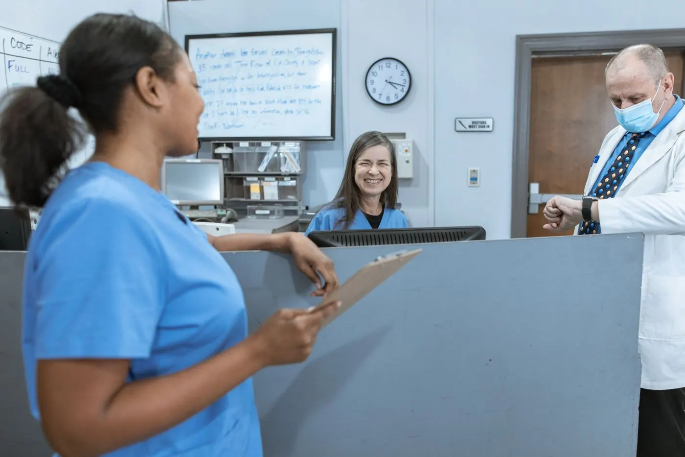 Two nurses smiling while working together at a hospital desk